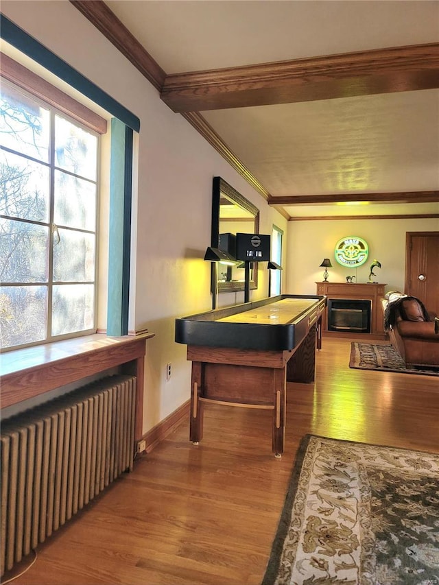 rec room with hardwood / wood-style floors, ornamental molding, and radiator