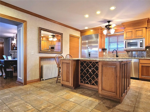 kitchen with a center island, built in appliances, ornamental molding, a kitchen bar, and radiator heating unit