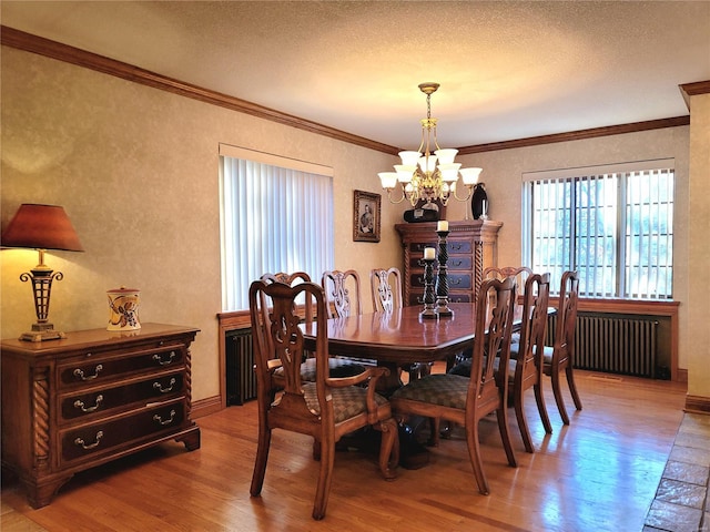 dining room with a textured ceiling, crown molding, wood-type flooring, an inviting chandelier, and radiator heating unit