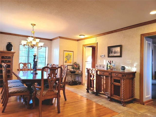 dining space featuring light hardwood / wood-style floors, ornamental molding, a textured ceiling, and an inviting chandelier