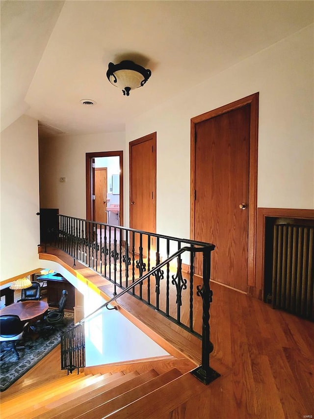 hallway with wood-type flooring and radiator heating unit