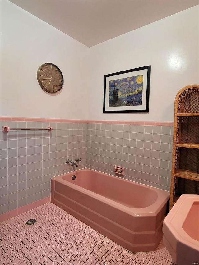 bathroom with tile patterned flooring, a tub to relax in, and tile walls