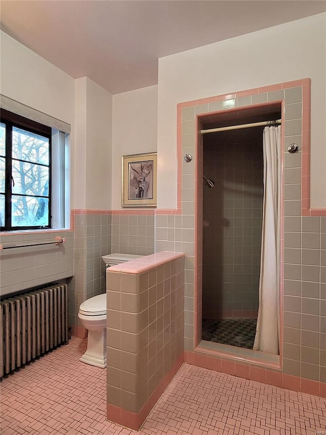 bathroom featuring radiator heating unit, toilet, tile walls, and curtained shower