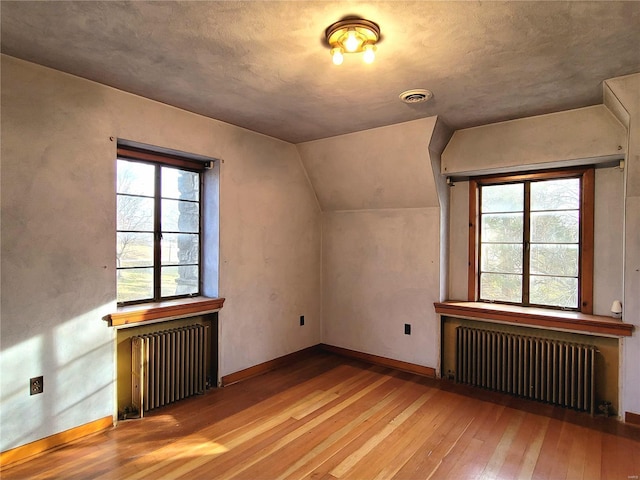 bonus room featuring light hardwood / wood-style floors, lofted ceiling, and radiator