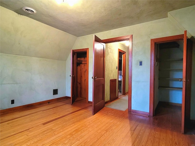 unfurnished bedroom featuring a closet, light hardwood / wood-style flooring, and lofted ceiling