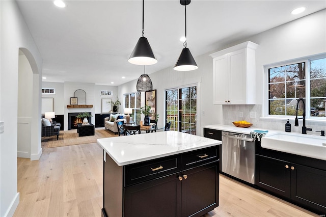 kitchen featuring hanging light fixtures, sink, light wood-type flooring, dishwasher, and tasteful backsplash