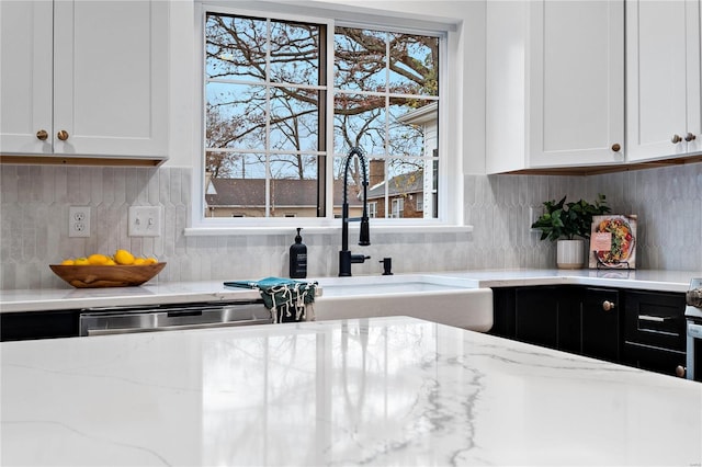 kitchen with light stone countertops, white cabinetry, and a wealth of natural light