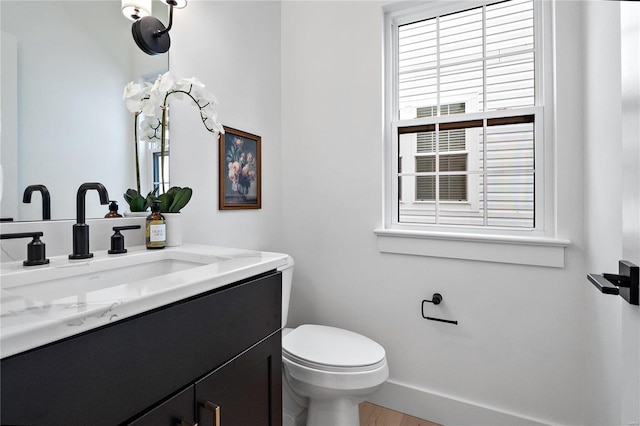 bathroom featuring toilet, a healthy amount of sunlight, hardwood / wood-style flooring, and vanity with extensive cabinet space