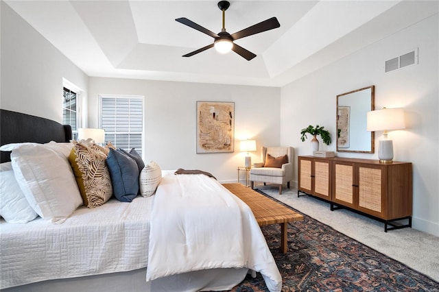 bedroom with a tray ceiling, ceiling fan, and light colored carpet