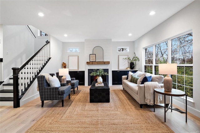 living room featuring brick wall, a large fireplace, and light hardwood / wood-style floors