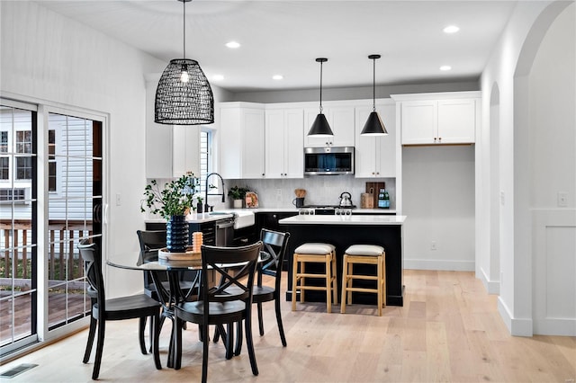 kitchen with a breakfast bar area, light hardwood / wood-style flooring, a wealth of natural light, and pendant lighting