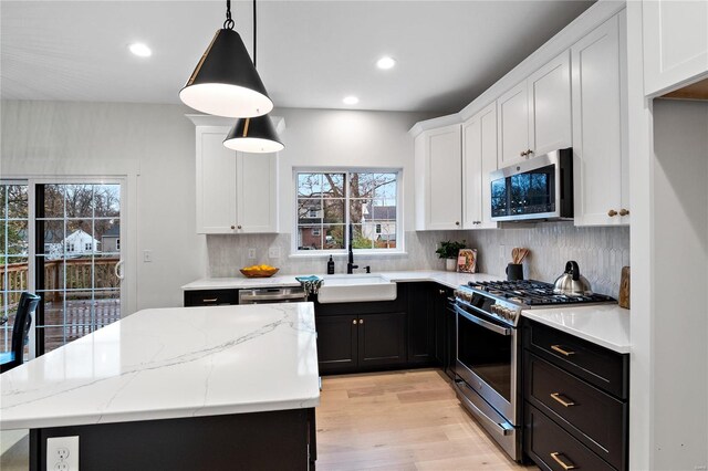 kitchen featuring light hardwood / wood-style flooring, stainless steel appliances, tasteful backsplash, and decorative light fixtures