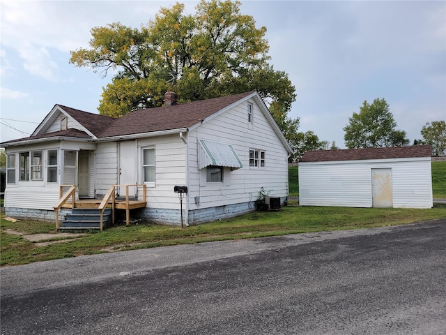 view of front of home featuring central AC unit, a front lawn, and an outdoor structure