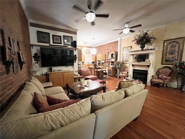 living room featuring crown molding, brick wall, ceiling fan with notable chandelier, and wood-type flooring