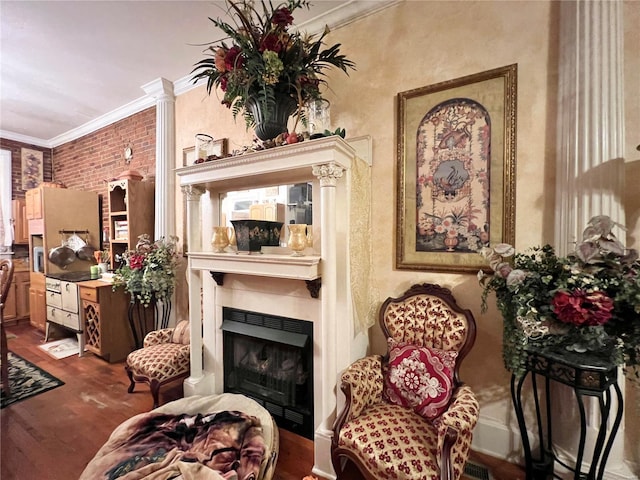 living area featuring brick wall, dark hardwood / wood-style floors, decorative columns, and ornamental molding