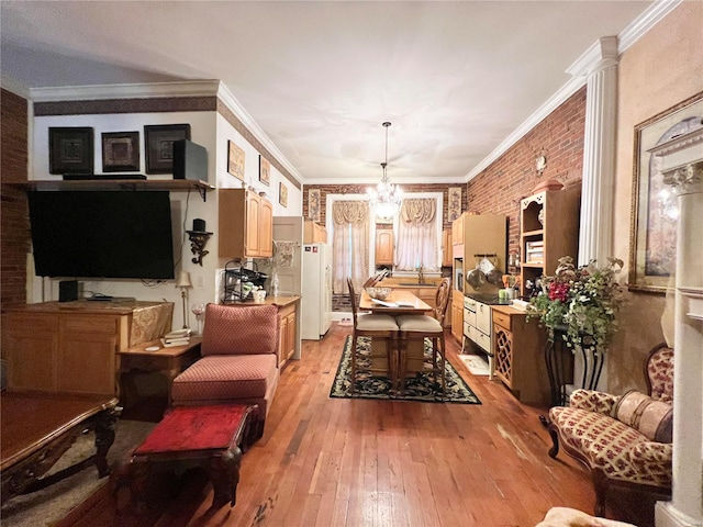 living room with a notable chandelier, crown molding, brick wall, and light hardwood / wood-style floors