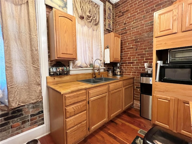 kitchen featuring brick wall, dark hardwood / wood-style floors, and sink