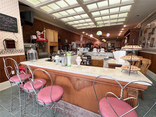 bar with brick wall, dark tile floors, and crown molding