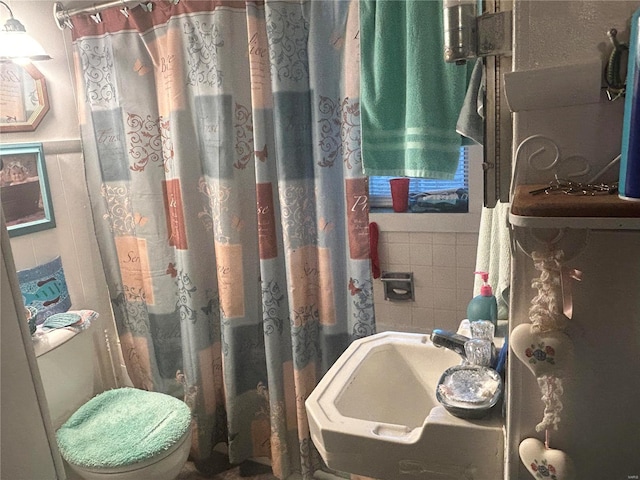 bathroom with sink, toilet, and tile walls