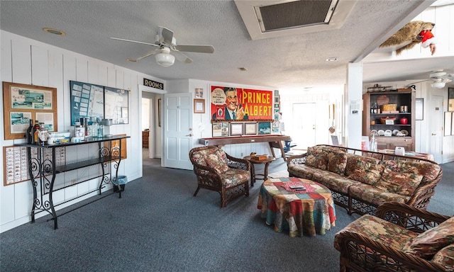 living room with dark carpet, ceiling fan, and a textured ceiling