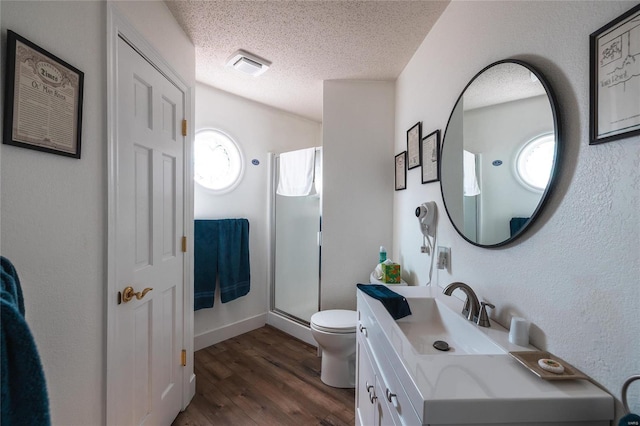 bathroom featuring walk in shower, hardwood / wood-style floors, a textured ceiling, toilet, and vanity