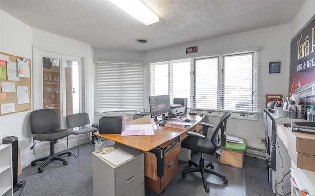 office featuring a textured ceiling, a wealth of natural light, and dark colored carpet