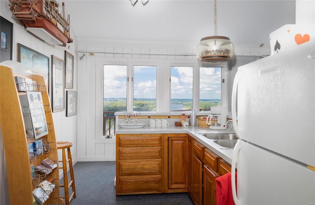 kitchen with hanging light fixtures, white refrigerator, dark carpet, and sink