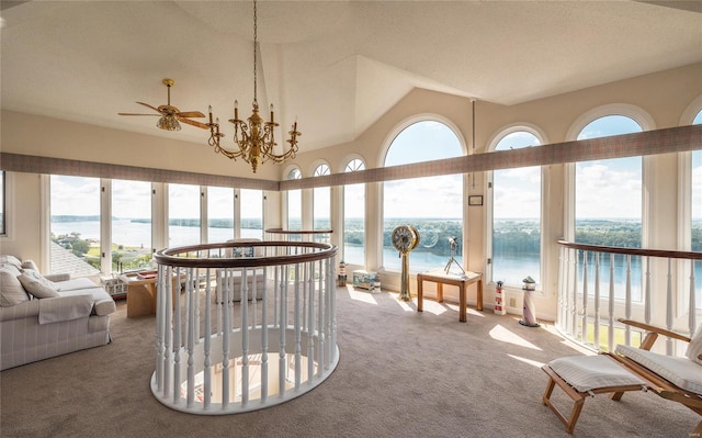 sunroom with ceiling fan with notable chandelier and a water view