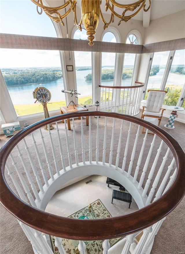 stairway with a water view, a chandelier, and carpet