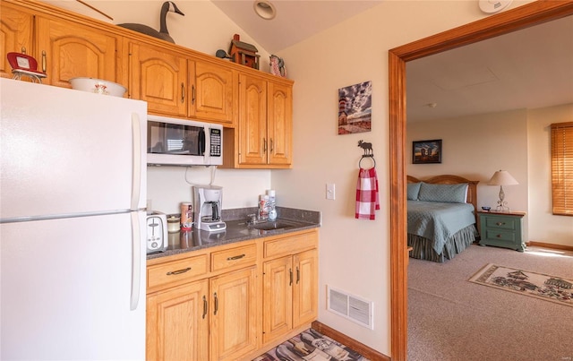 kitchen with carpet flooring, white appliances, sink, and vaulted ceiling