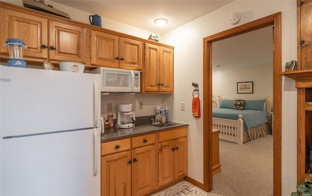 kitchen featuring sink, white appliances, and light colored carpet