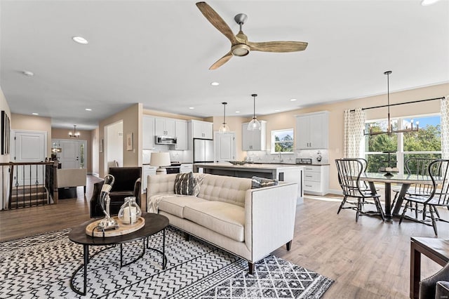 living room featuring light hardwood / wood-style floors and ceiling fan with notable chandelier