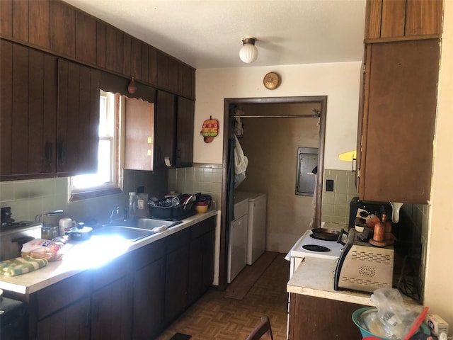 kitchen featuring sink, washing machine and clothes dryer, dark parquet flooring, and tasteful backsplash