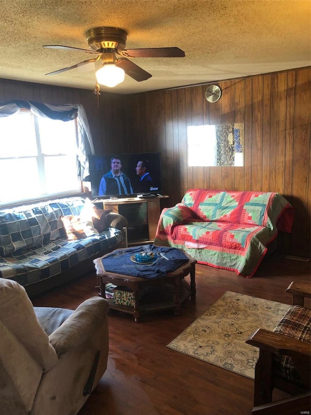 living room featuring a textured ceiling, dark hardwood / wood-style floors, wooden walls, and ceiling fan