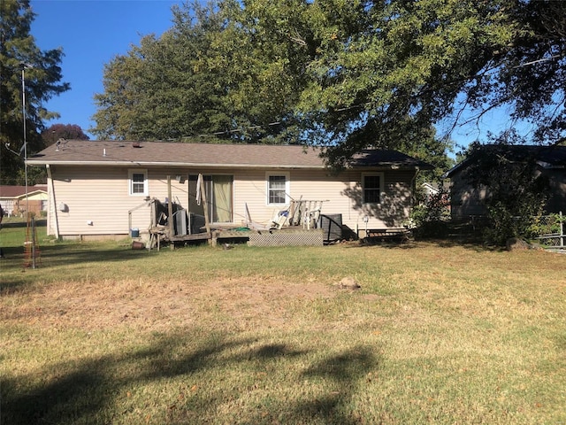 back of property with a wooden deck and a lawn