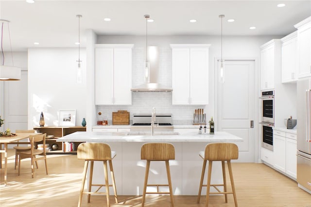 kitchen featuring hanging light fixtures, white cabinets, and a kitchen island with sink