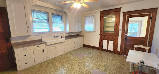 kitchen with sink, white cabinets, ceiling fan, and light tile flooring