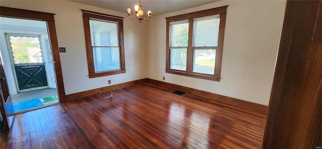 spare room featuring dark hardwood / wood-style floors and an inviting chandelier