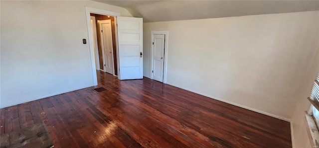 unfurnished room with vaulted ceiling and dark wood-type flooring