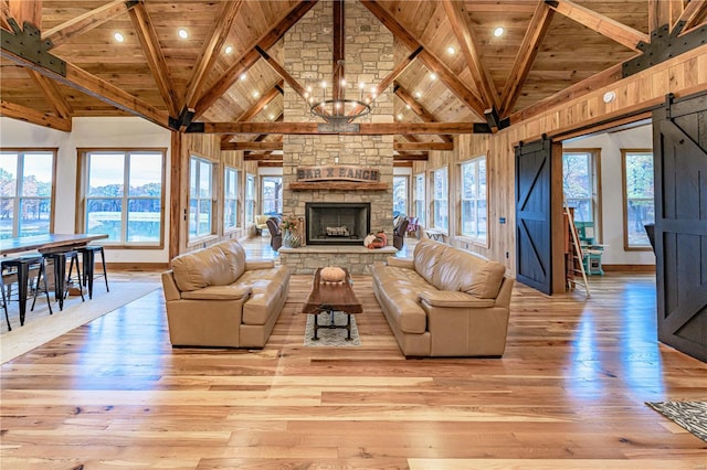 unfurnished living room featuring beamed ceiling, light wood-type flooring, and a barn door