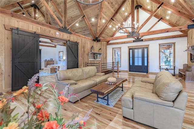 living room featuring light wood-type flooring, a barn door, and beam ceiling