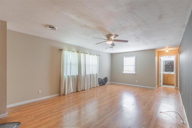 spare room featuring light hardwood / wood-style flooring, ceiling fan, and a textured ceiling