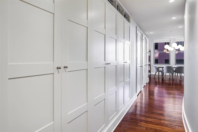 hallway featuring a notable chandelier and dark hardwood / wood-style flooring