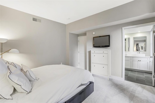 carpeted bedroom with ensuite bath and sink