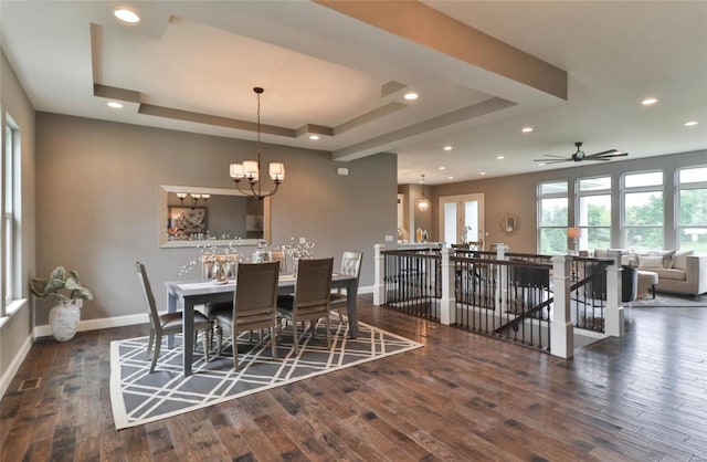 dining space featuring ceiling fan with notable chandelier, dark hardwood / wood-style floors, and a tray ceiling