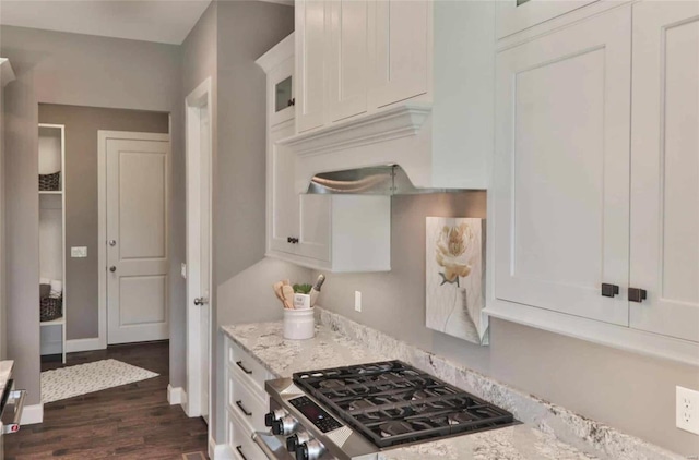 kitchen featuring light stone countertops, white cabinetry, dark wood-type flooring, and stainless steel gas range oven