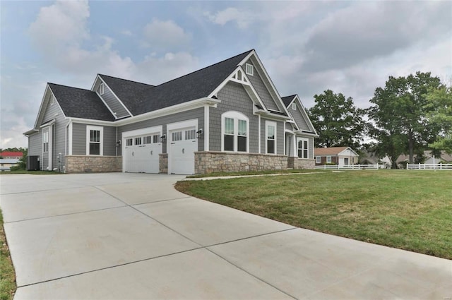 craftsman-style home featuring central air condition unit, a front lawn, and a garage