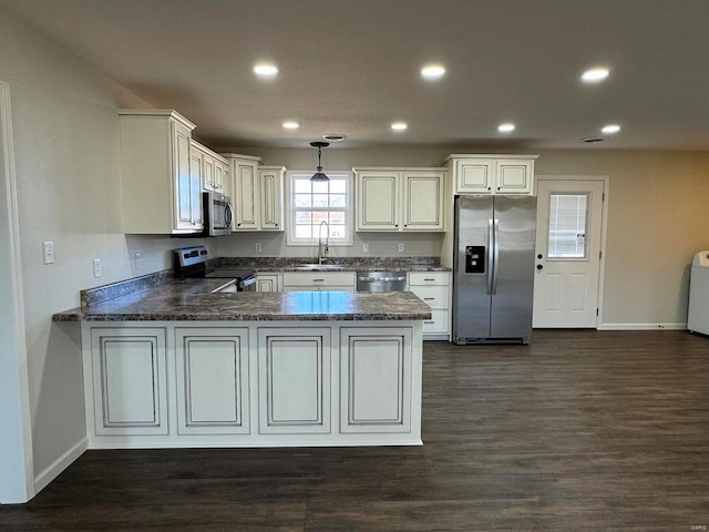 kitchen featuring sink, kitchen peninsula, appliances with stainless steel finishes, and dark hardwood / wood-style flooring