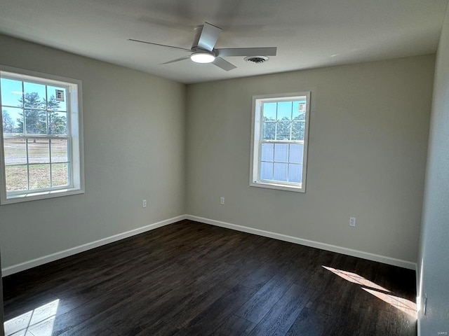 empty room with plenty of natural light, ceiling fan, and dark wood-type flooring