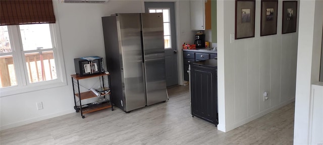 kitchen with light hardwood / wood-style flooring, stainless steel refrigerator, and a wall mounted AC